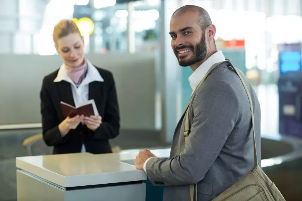 smiling-commuter-standing-counter-while-attendant-checking-his-passport